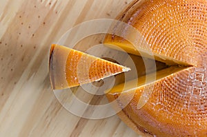 Top view of cheese wheel and slice over a wooden table