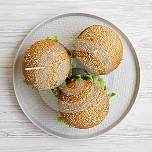 Top view, cheeseburgers on grey plate on white wooden background. Flat lay, overhead, from above