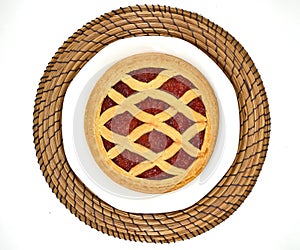 Top view of a cherry jam tart pie on plate and round tablemat.