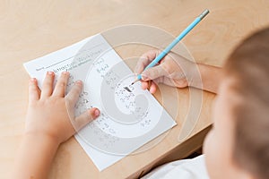 Top view of child hands with pencils. Solving maths exercises