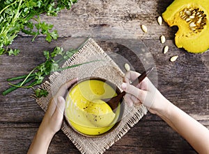 Top view child hands with pumpkin soup. flat lay rustic background