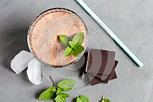 Top view of a chocolate cocktail, smoothie with ice, chocolate pieces and mint in a glass glass. Cooling drinks, desserts in the