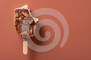 Top view chocolate outer ice cream with peanuts on a brown background with bites