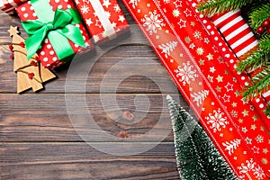 Top view of Christmas background made of fir tree, rolled wrapping paper and other decorations on wooden background. New year