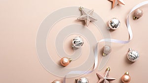 Top view Christmas balls, stars and ribbon on copper or champagne pink background. Flat lay glamour stylish fashion decorations.