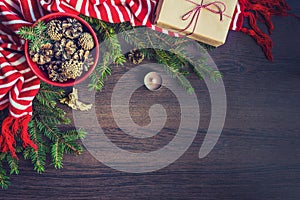 Top view of christmas decoration - red bowl full of fir-cones, gift box wrapped in kraft paper, golden angel, pine branches, candl