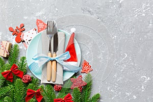 Top view of Christmas dinner on cement background. Plate, utensil, fir tree and holiday decorations with copy space. New Year time