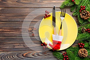 Top view of Christmas dinner on wooden background. Plate, utensil, fir tree and holiday decorations with copy space. New Year time