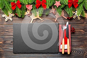 Top view of Christmas dinner on wooden background. Plate, utensil, fir tree and holiday decorations with copy space. New Year time
