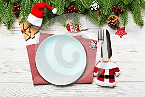 Top view of Christmas dinner on wooden background. Plate, utensil, fir tree and holiday decorations with copy space. New Year time