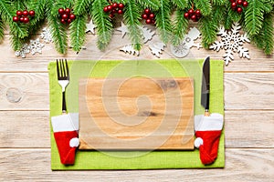 Top view of Christmas dinner on wooden background. Plate, utensil, fir tree and holiday decorations with copy space. New Year time