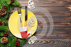 Top view of Christmas dinner on wooden background. Plate, utensil, fir tree and holiday decorations with copy space. New Year time