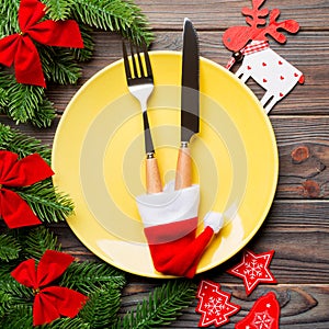 Top view of Christmas dinner on wooden background. Plate, utensil, fir tree and holiday decorations with copy space. New Year time