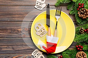 Top view of Christmas dinner on wooden background. Plate, utensil, fir tree and holiday decorations with copy space. New Year time