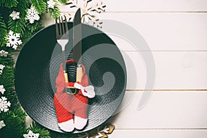 Top view of Christmas dinner on wooden background. Plate, utensil, fir tree and holiday decorations with copy space. New Year time