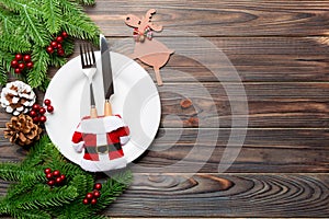 Top view of Christmas dinner on wooden background. Plate, utensil, fir tree and holiday decorations with copy space. New Year time