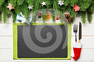 Top view of Christmas dinner on wooden background. Plate, utensil, fir tree and holiday decorations with copy space. New Year time