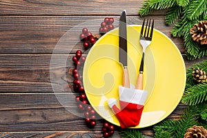 Top view of Christmas dinner on wooden background. Plate, utensil, fir tree and holiday decorations with copy space. New Year time