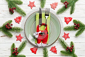 Top view of Christmas dinner on wooden background. Plate, utensil, fir tree and holiday decorations. New Year time concept