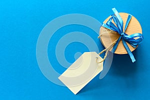 Top view on Christmas gift box decorated with ribbon on blue paper background.