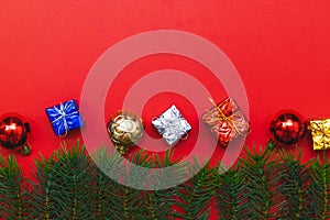 Top view of Christmas gift box red balls with spruce branches, pine cones, red berries and bell on red background