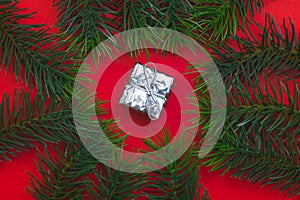 Top view of Christmas gift box red balls with spruce branches, pine cones, red berries and bell on red background