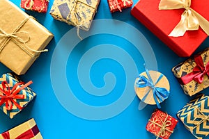 Top view on Christmas gifts wrapped in gift paper decorated with ribbon on blue paper background