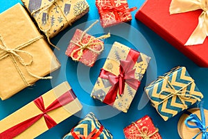 Top view on Christmas gifts wrapped in gift paper decorated with ribbon on blue paper background.