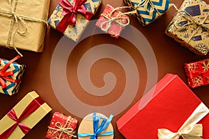 Top view on Christmas gifts wrapped in gift paper decorated with ribbon on brown paper background.