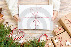 Top view of christmas letter in hand. Close up of hands holding empty wishlist on wooden table with xmas decoration