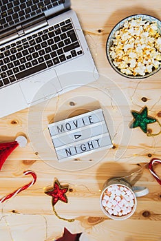 Top view Christmas Movie night concept. Flat lay composition with Movie night message on the board, laptop, popcorn bowl