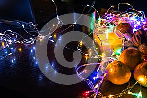 Top view. Christmas New Year Composition with Tangerines candle, garlands, colorful lights, selective focus Black Background