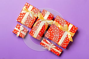 Top view Christmas present box with gold bow on purple background