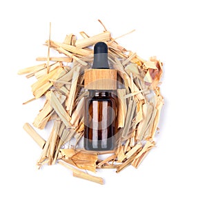 Top view of citronella essential oil in glass bottle on dried lemongrass sticks isolated on white background.