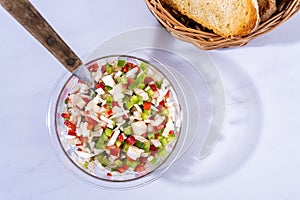 Top view of a classic bell pepper and onion vinaigrette with vinegar and olive oil in a transparent bowl. Healthy and natural food photo