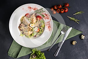 Top view on classic Caesar salad with grilled chicken breast and half of quail eggs in white ceramic plate. Green tablecloth,