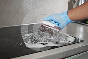 Top view Cleaning a ceramic electric stove with a metal scraper.