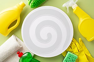 Top view of cleaning supplies - detergent products, dust cloth, rubber gloves, brush, and sponge on soothing green background