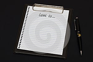 Top view of clipboard and white sheet written with Lve is on black background