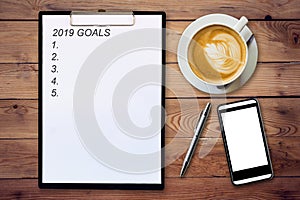 Top view of clipboard written Goals 2019 on wooden background wi