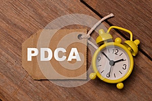 Top view of clock and memo note written with PDCA stands for Plan Do Check Act or Plan Do Check Adjust