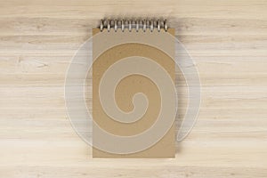 Top view and close up of brown spring note pad on wooden desktop background. Mock up place for your advertisement. Education, work