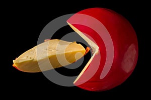 Top view. Close up. Head of Dutch cheese Edam and sliced piece. Isolated on black background