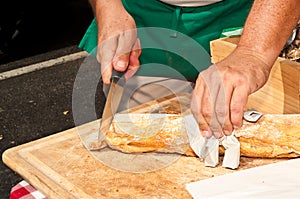Top view, close up of a man slicing a freshly baked baguette