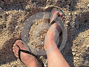 Top view close up of man wearing blue flip flops walking along tropical exotic ocean beach