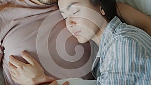 Top view close-up of man and woman sleeping in bed together hugging lying under warm blanket