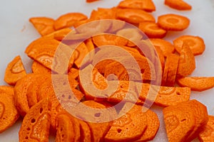 Top view close up of sliced raw carrots on round slices on a white background
