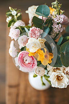 Top view close-up vibrant and colorful bouquet of flowers in a white vase