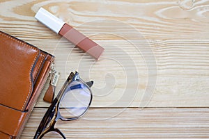 Top view close up woman wallet, glasses and lipstick with wooden background