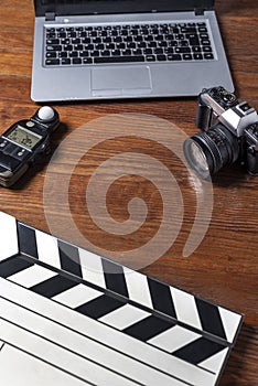 Top view closeup of cameras, notebook, photometer, and a movie clapperboard on a wooden table photo